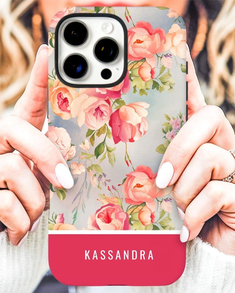 A person's hands holding a phone case with a floral design and the name Kassandra on a pink band at the bottom.