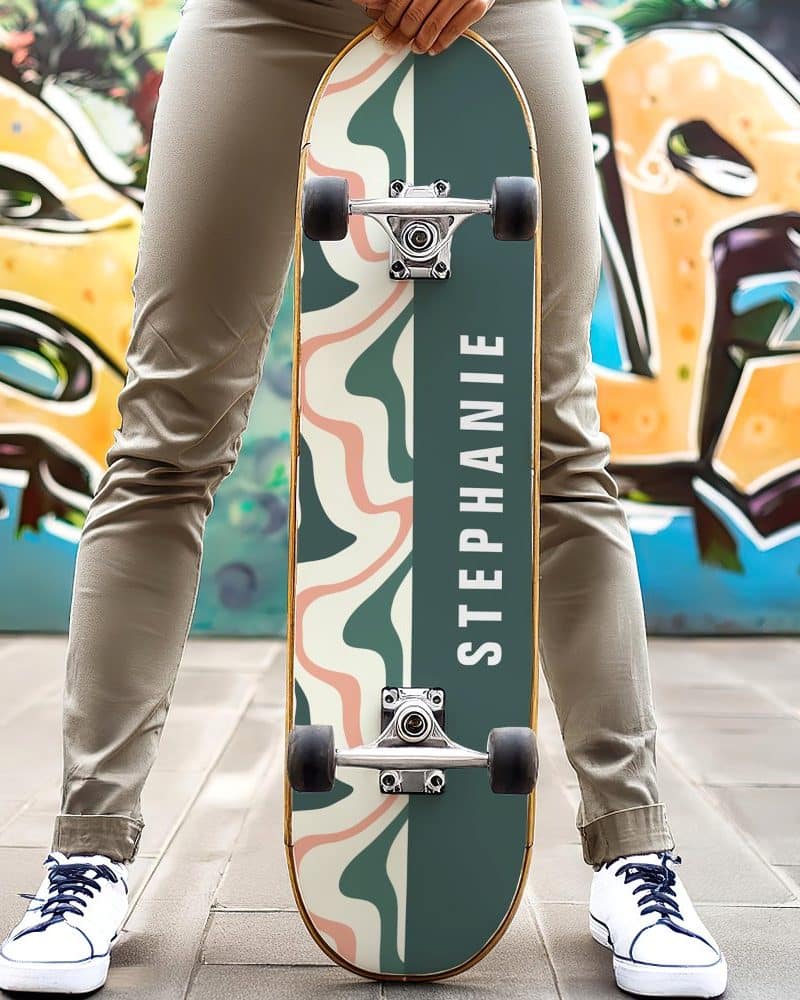 Person holding a personalized skateboard with an abstract design and the name Stephanie.