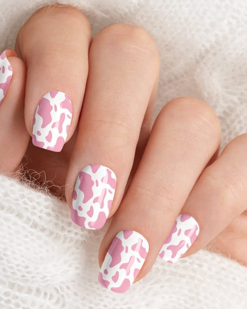 Closeup of a hand with pink cow print nail art.