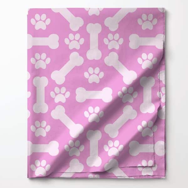 Pink Fabric With A Repeating Pattern Of White Paw Prints And Bones.
