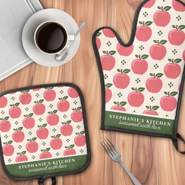 A Pair Of Oven Mitts And A Pot Holder Featuring A Pink Apple Pattern And Personalized Text.