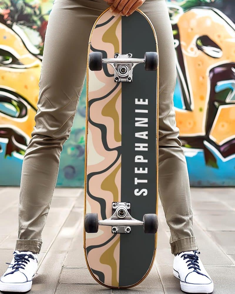 Person holding a personalized skateboard with an abstract design and the name Stephanie.