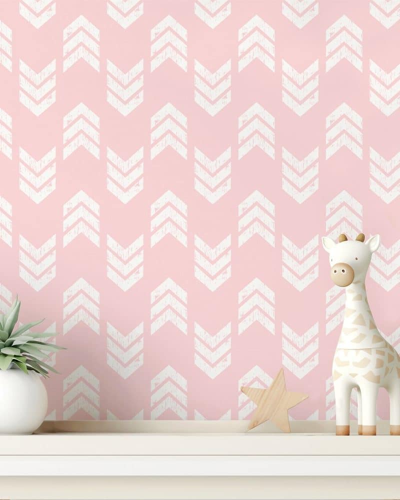 Pink wall with a white chevron pattern, featuring a small giraffe toy and a succulent plant on a shelf.