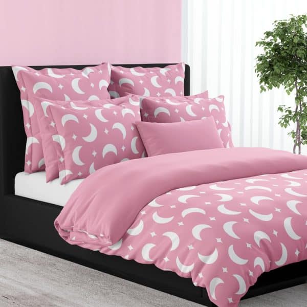 Pink Duvet Cover And Pillows With A White Crescent Moon And Star Pattern.