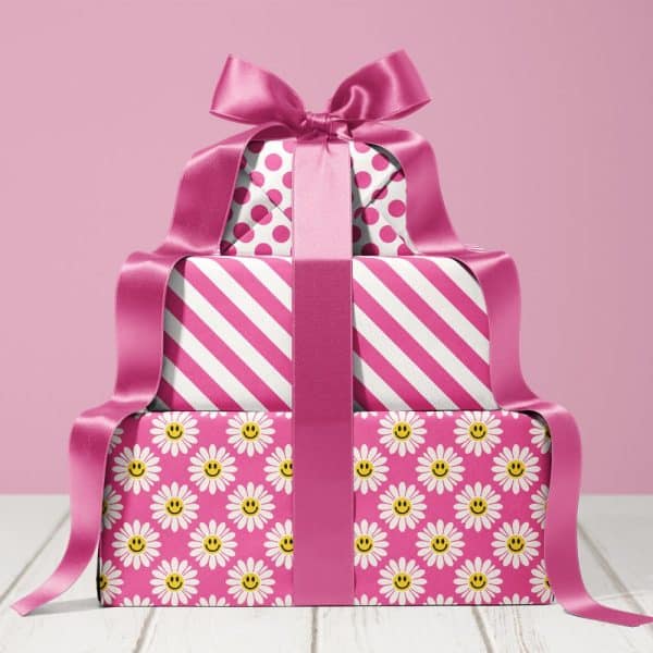 Stack Of Three Pink Gift Boxes With A Large Pink Ribbon. The Boxes Are Wrapped In Different Pink And White Patterns.