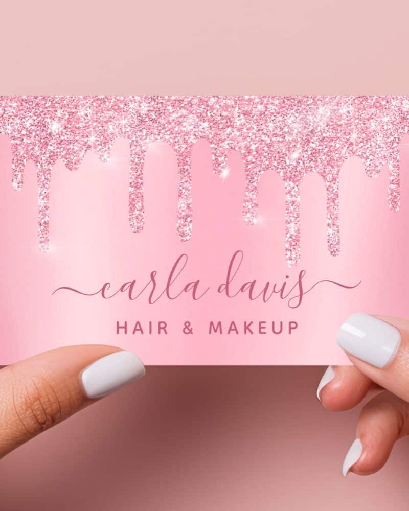Pink glitter drips across a light pink business card that says Carla Davis Hair & Makeup.