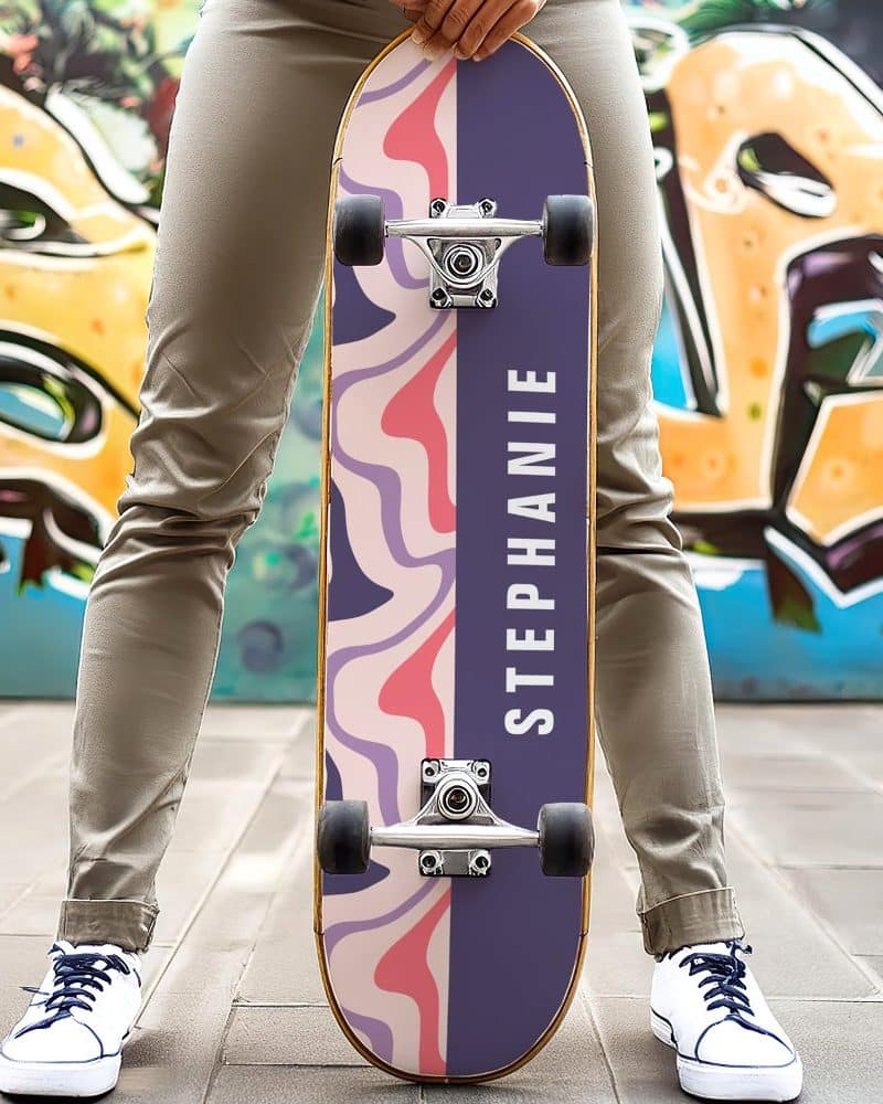 Person holding a purple and pink skateboard with the name Stephanie on it.