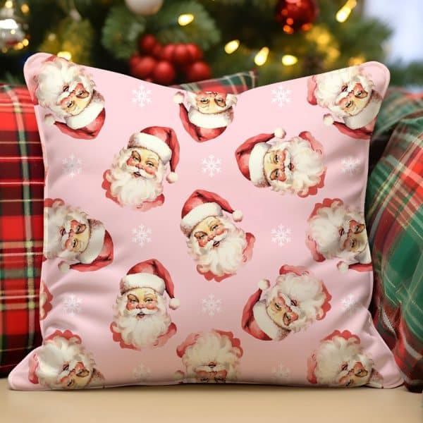 Pink Pillow With Repeating Pattern Of Santa Claus Faces And Snowflakes.