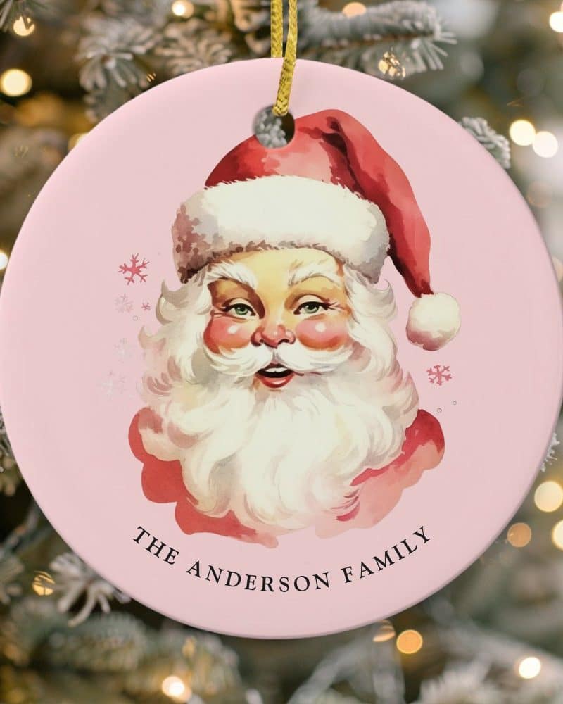 Pink round Christmas ornament featuring a vintage illustration of Santa Claus's face, with the text The Anderson Family below.