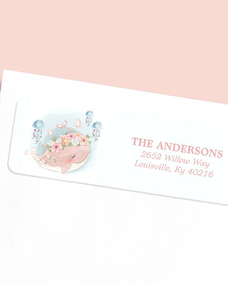 Return address label featuring a pink whale wearing a flower crown, surrounded by jellyfish and butterflies.