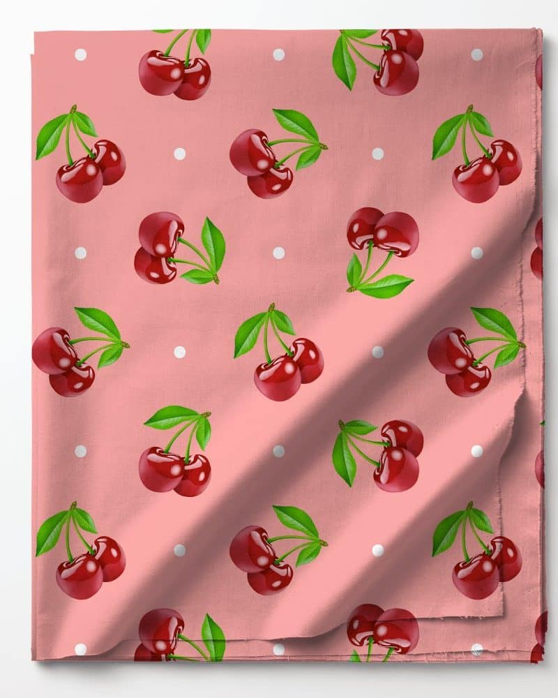 Pink fabric with a repeating pattern of red cherries and white dots.