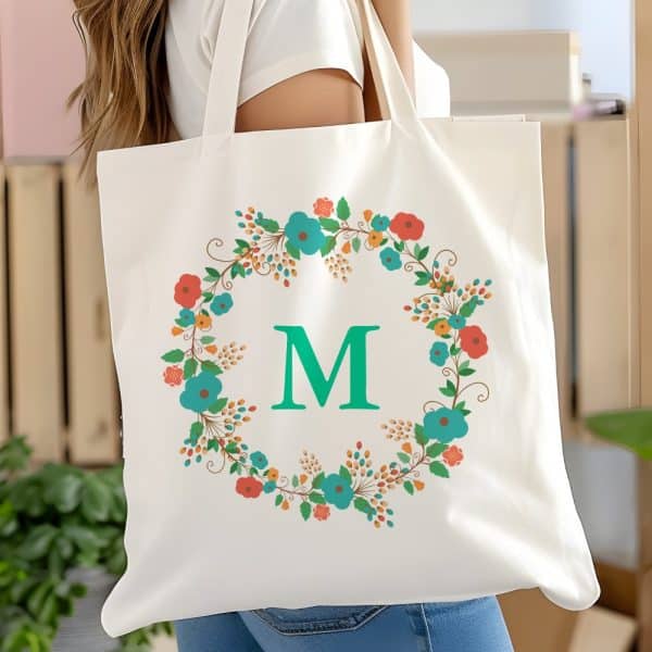 White Tote Bag With A Teal Initial M Centered In A Floral Wreath.