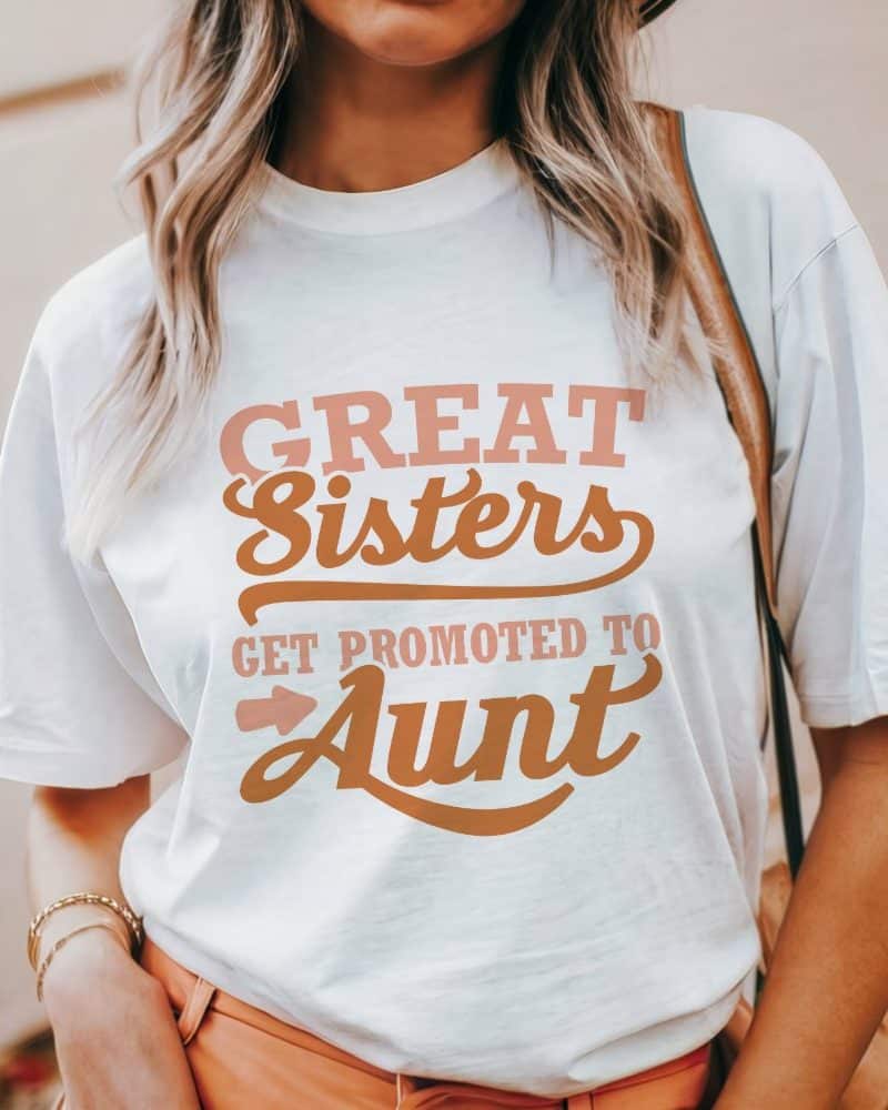 Woman wearing a white t-shirt with the text Great Sisters Get Promoted To Aunt.