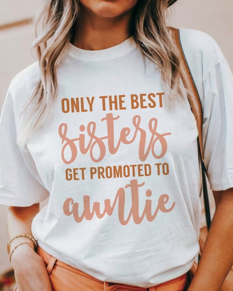 Woman wearing a white t-shirt that says Only the best sisters get promoted to auntie.