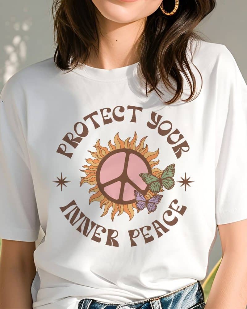 Woman wearing a white t-shirt with a peace symbol in a sun design and the text Protect Your Inner Peace.