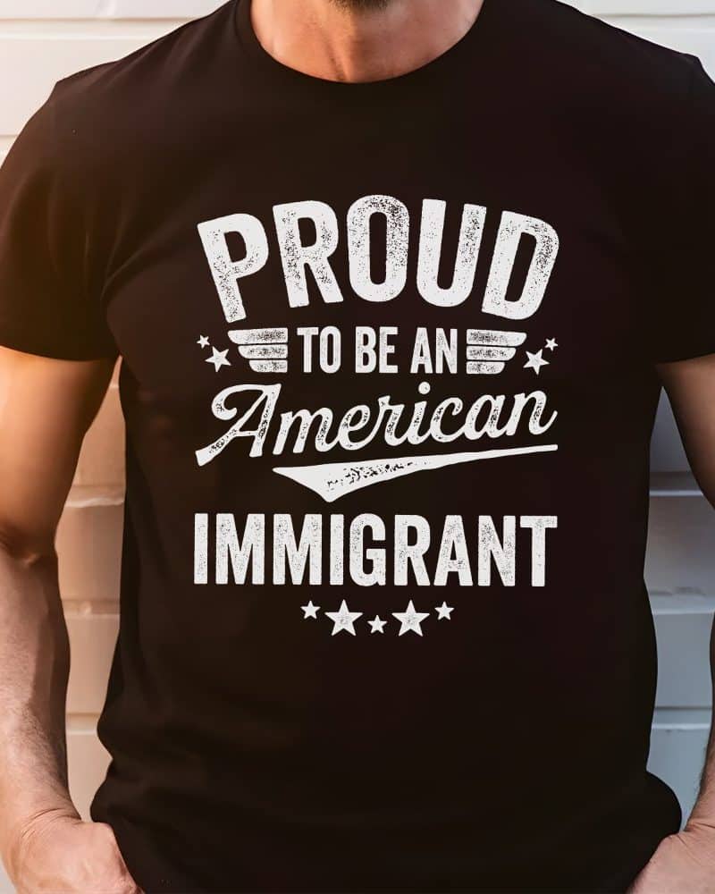 Person wearing a black t-shirt that says Proud to be an American Immigrant.