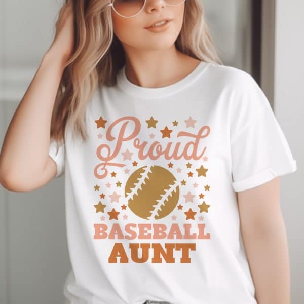 Woman Wearing A White T-Shirt That Says Proud Baseball Aunt, Surrounded By Stars And A Baseball Graphic.