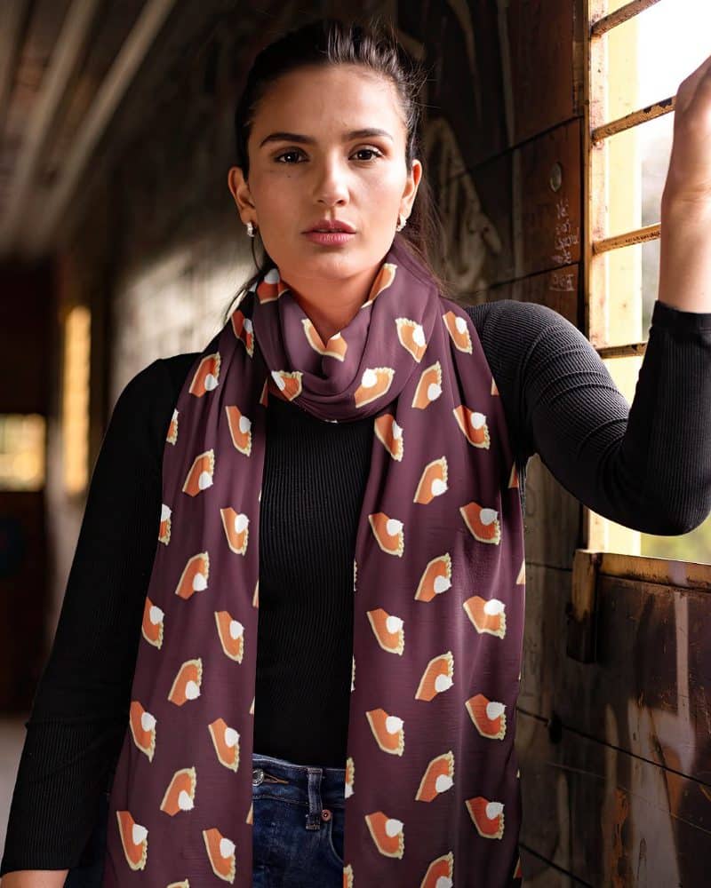 Woman wearing a maroon scarf printed with pumpkin pie slices.