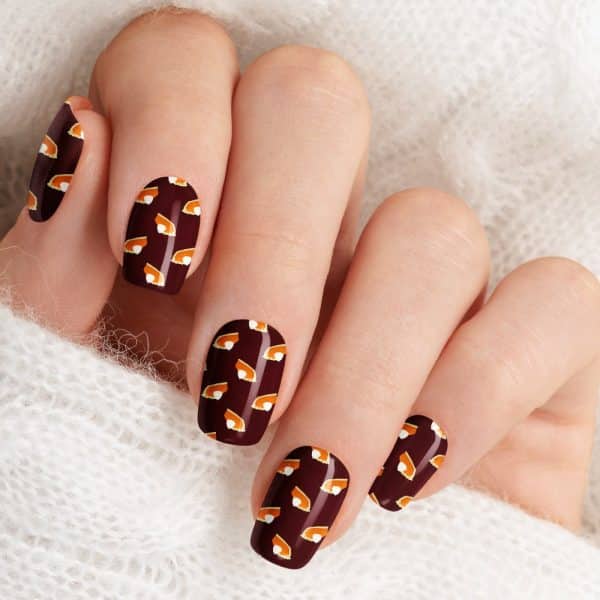 Close-Up Of A Hand With Fingernails Painted Dark Brown And Decorated With A Pattern Of Small Pumpkin Pie Images.
