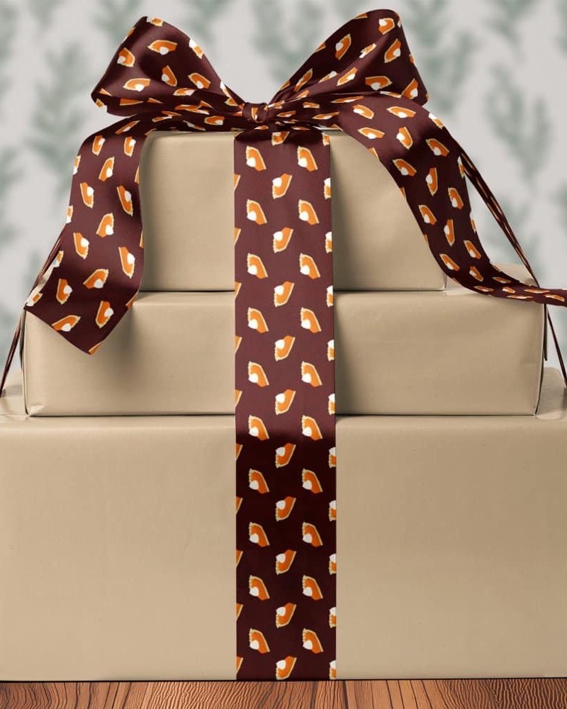 Three stacked presents tied with a brown ribbon featuring a pattern of pumpkin pie slices.