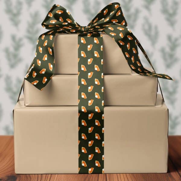 Three Stacked, Wrapped Gifts Tied With A Dark Green Ribbon Patterned With Pumpkin Pie Slices.