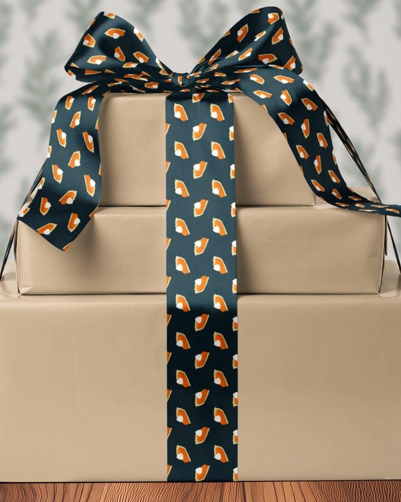 Three stacked presents tied with a dark ribbon featuring a pattern of pumpkin pie slices.