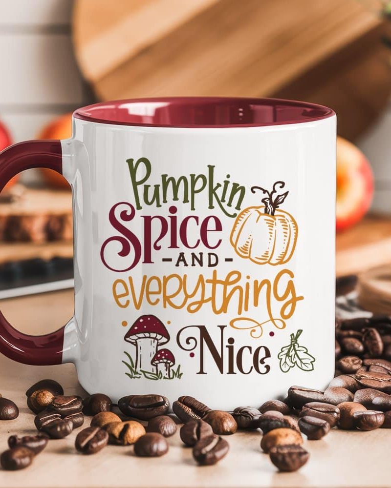 White mug with burgundy interior, featuring autumnal text and graphics that read Pumpkin Spice and Everything Nice.