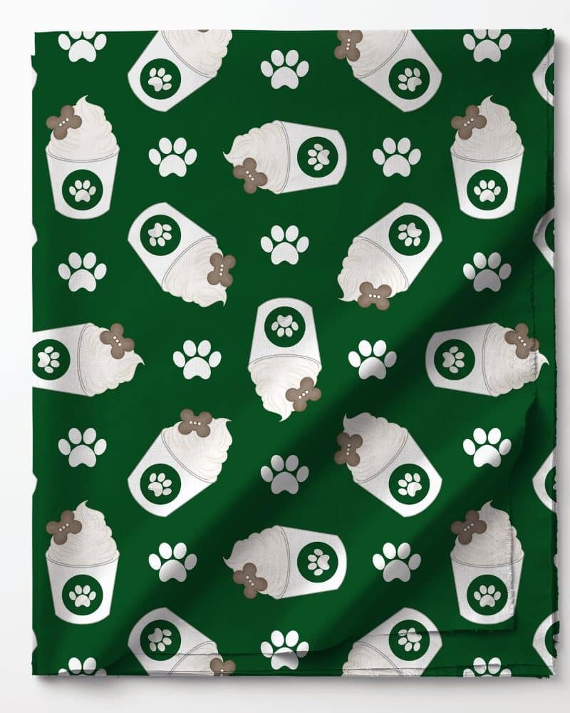 Green fabric with a repeating pattern of coffee cups topped with whipped cream and a dog bone, and paw prints.