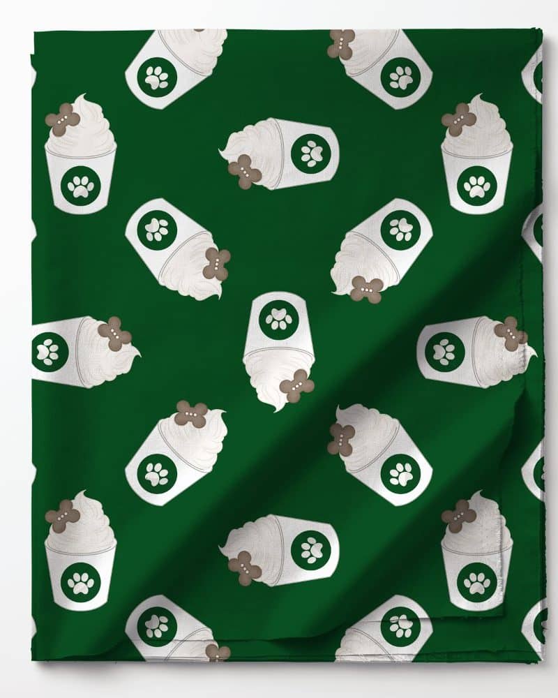 Dark green fabric with a repeating pattern of white cups of frothy beverage topped with a brown dog treat. Each cup has a paw print.