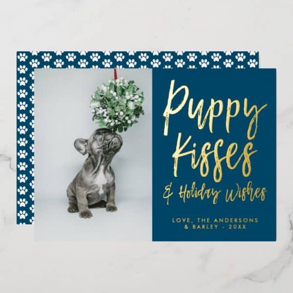 A Navy Blue Christmas Card Featuring A Photo Of A French Bulldog Puppy Looking Up At A Mistletoe Sprig. Gold Lettering Reads Puppy Kisses &Amp; Holiday Wishes.