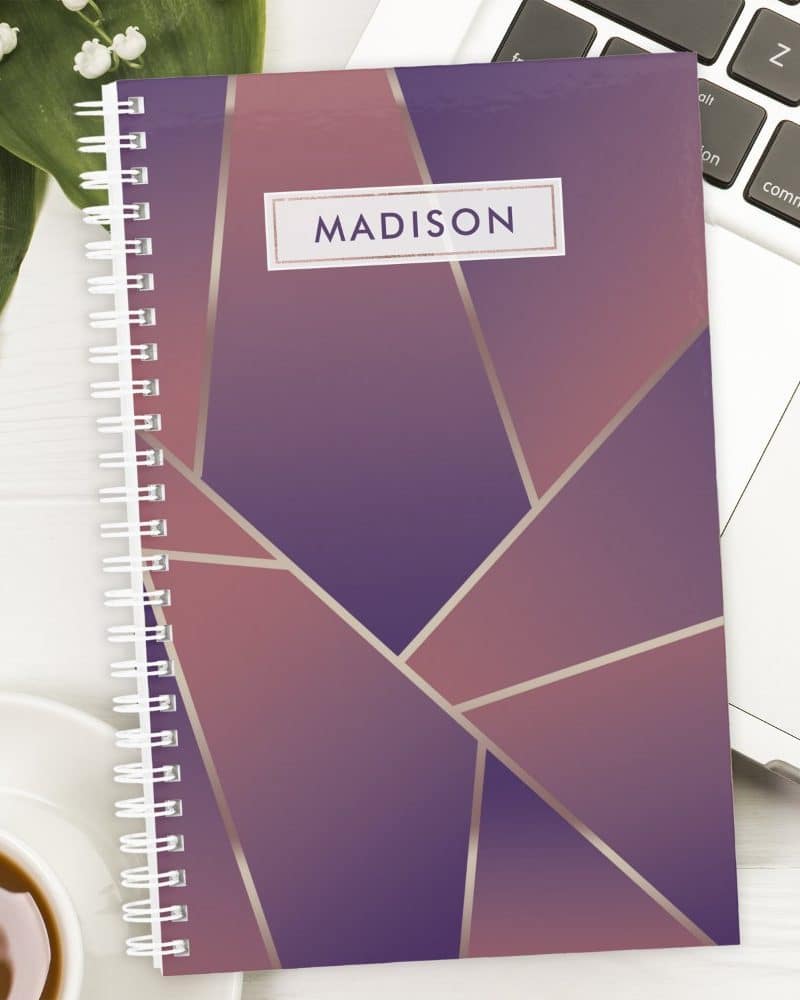 Spiral-bound notebook with a purple and rose gold geometric design and the name Madison on the cover.