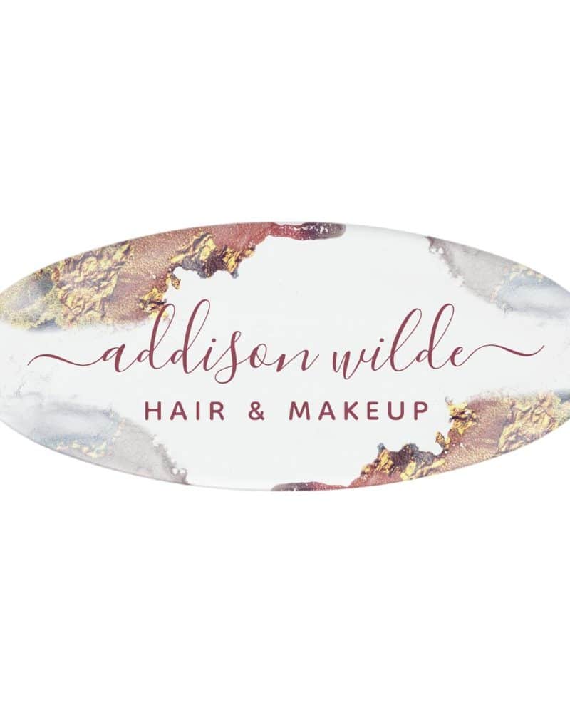Oval logo for Addison Wilde Hair & Makeup. The logo features a watercolor-style design in gold and burgundy.