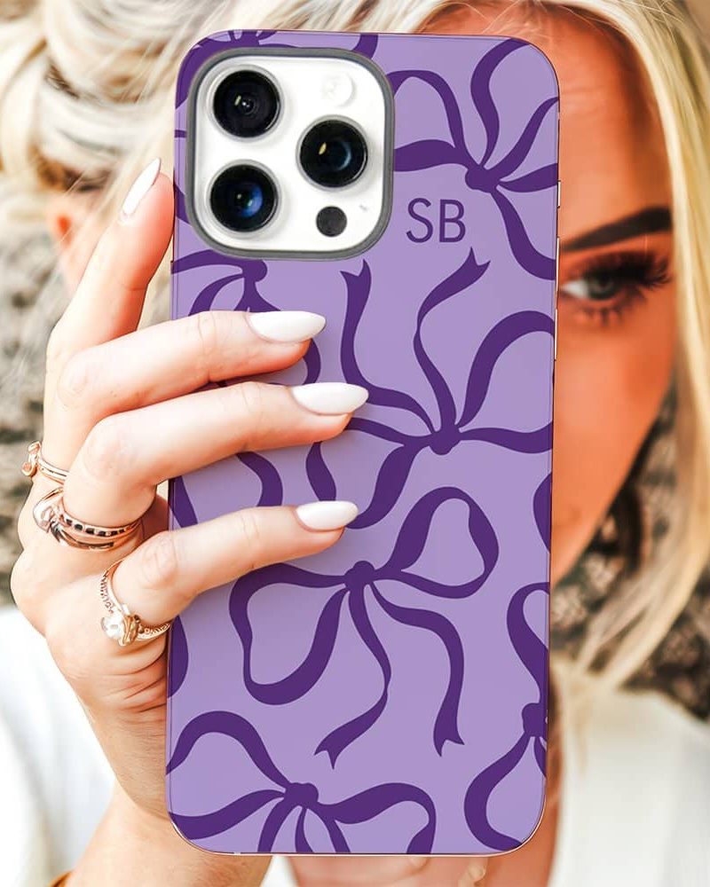 A woman holds up a lavender phone case with a purple bow pattern and initials SB.