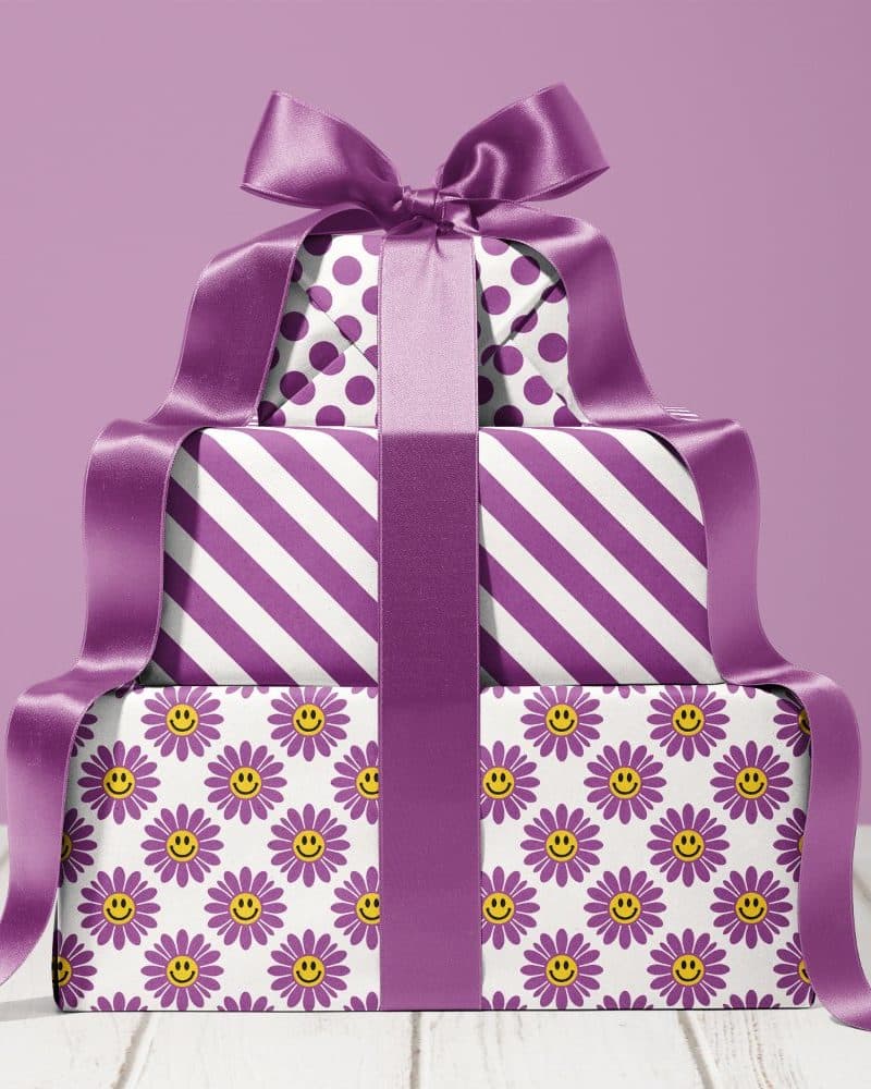 A stack of three presents wrapped in purple and white patterned paper, tied with a large purple ribbon.