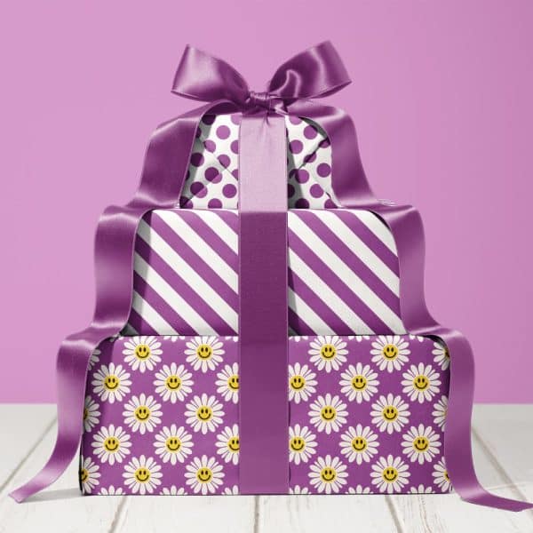 A Stack Of Three Gifts Wrapped In Purple Paper With Different Patterns: Polka Dots, Stripes, And Daisies With Smiley Faces. A Large Purple Ribbon Is Tied Around The Entire Stack.