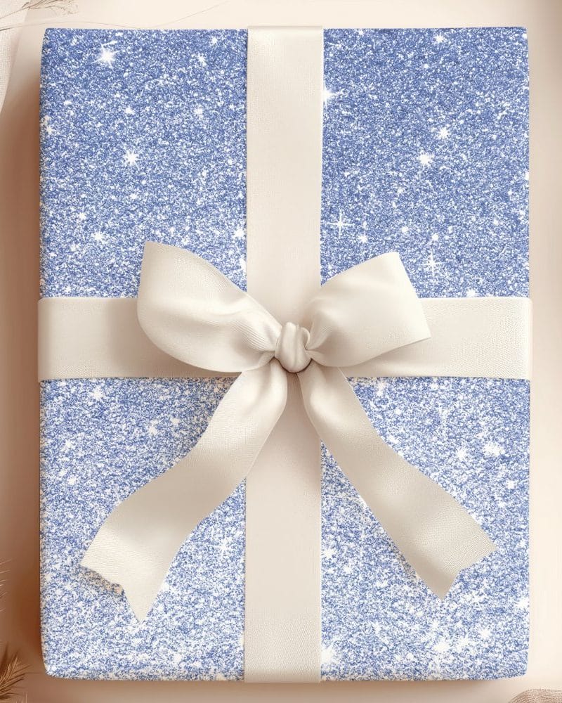 A light blue glitter gift box with a cream-colored ribbon tied in a bow.
