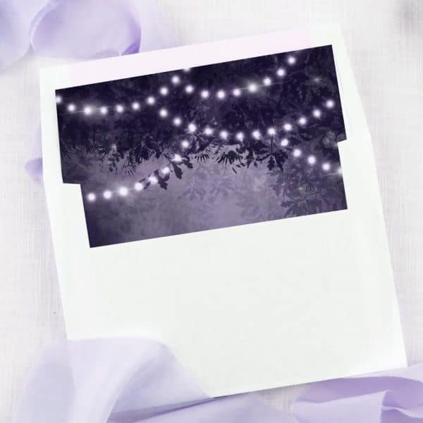 White Envelope With A Dark Purple Liner Featuring String Lights Draped Through Trees.