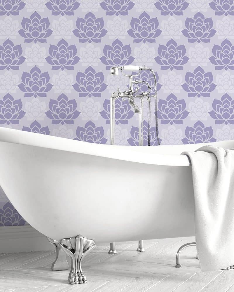 A clawfoot bathtub in front of a lavender floral wall.
