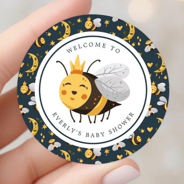 A Round Baby Shower Invitation Featuring A Cartoon Bee Wearing A Crown. The Bee Is Yellow And Black And Is Surrounded By A Dark Blue Background With Stars And Moons. The Text Reads Welcome To Everly'S Baby Shower.