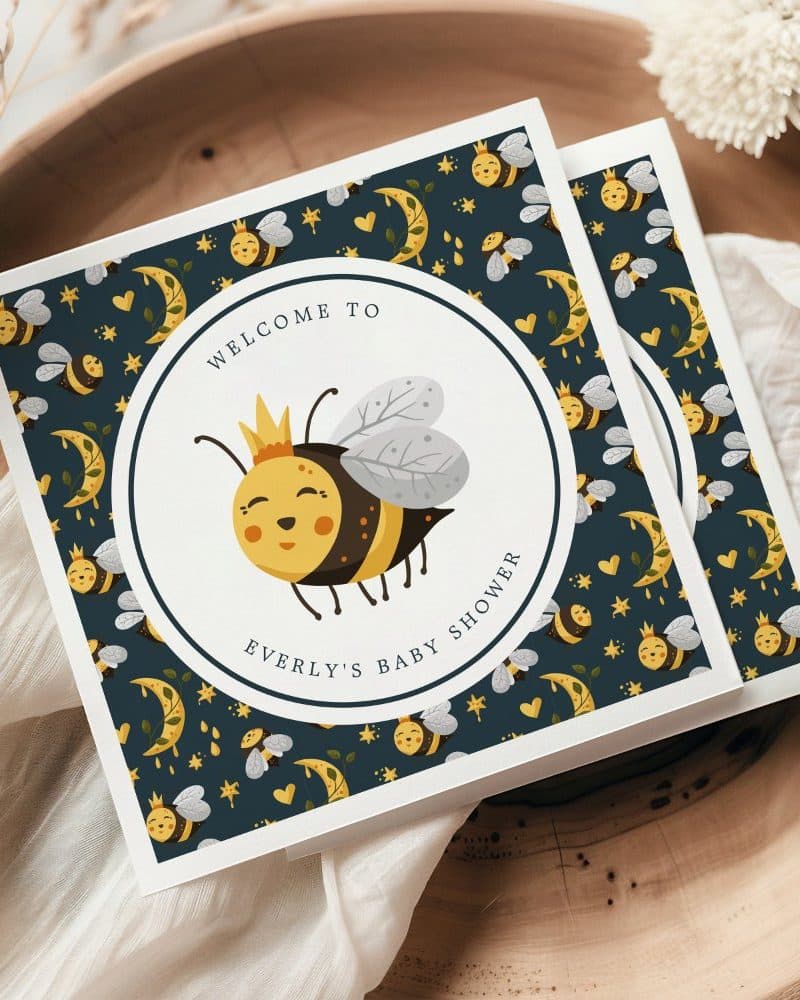 Baby shower invitation featuring a cartoon bee wearing a crown. The invitation has a dark background with a repeating pattern of bees, moons, and stars.
