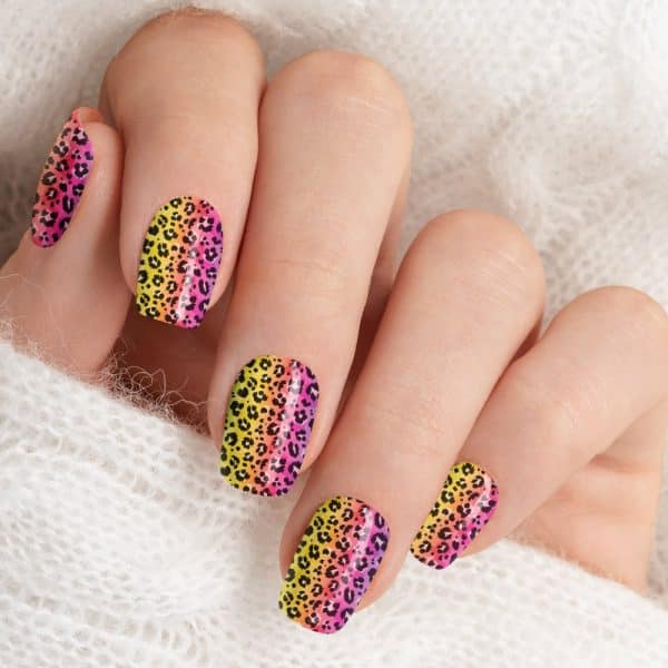 Hand With Vibrant Ombre Leopard Print Nail Art.