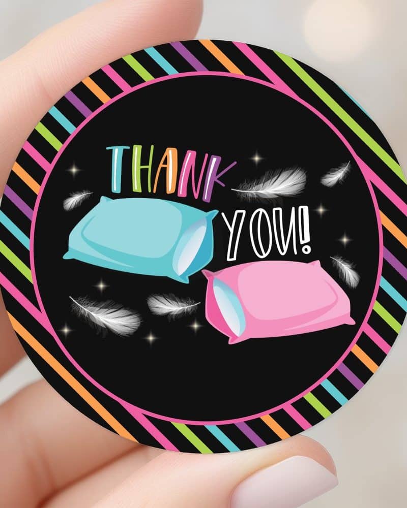 Round thank you sticker with a black background, neon stripes, two pillows, and white feathers.