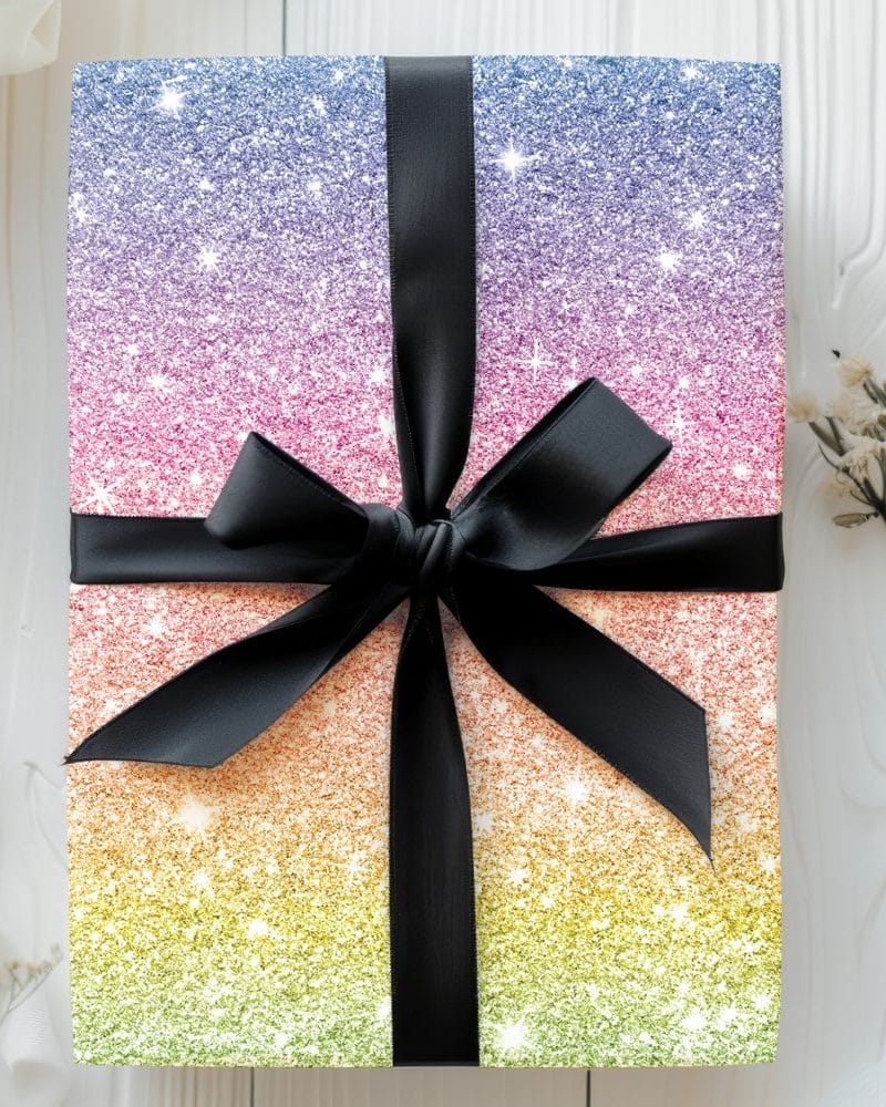A gift wrapped in rainbow glitter paper with a black ribbon.