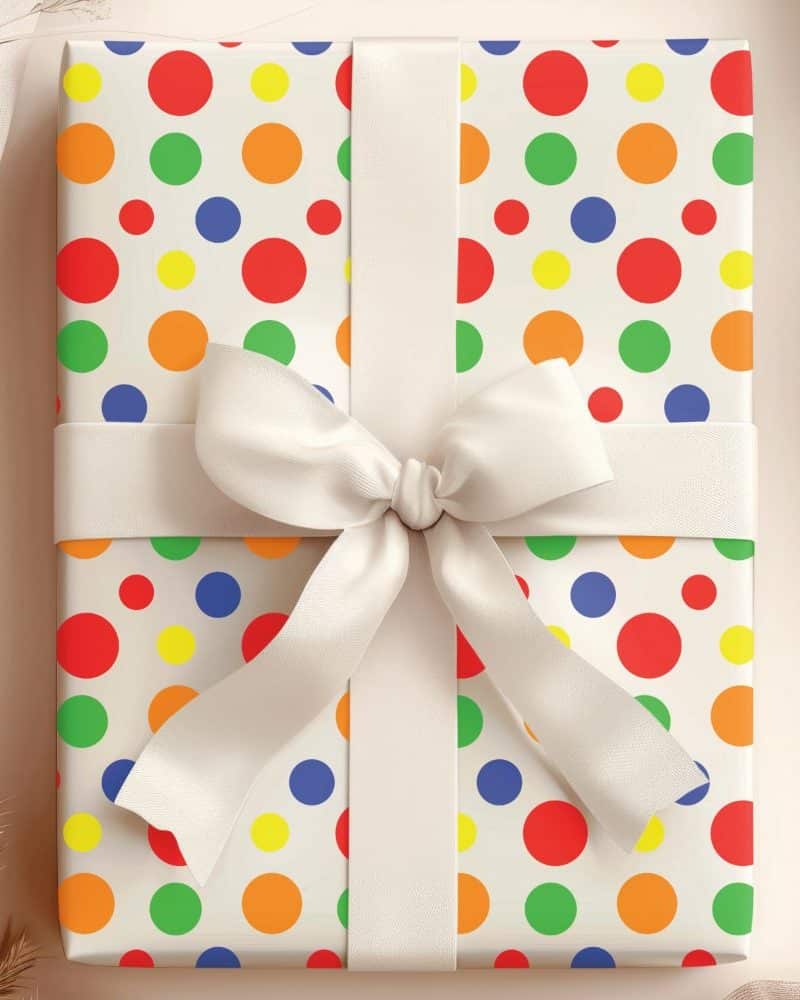 A gift wrapped in off-white paper with a colorful polka dot pattern and a cream-colored ribbon.