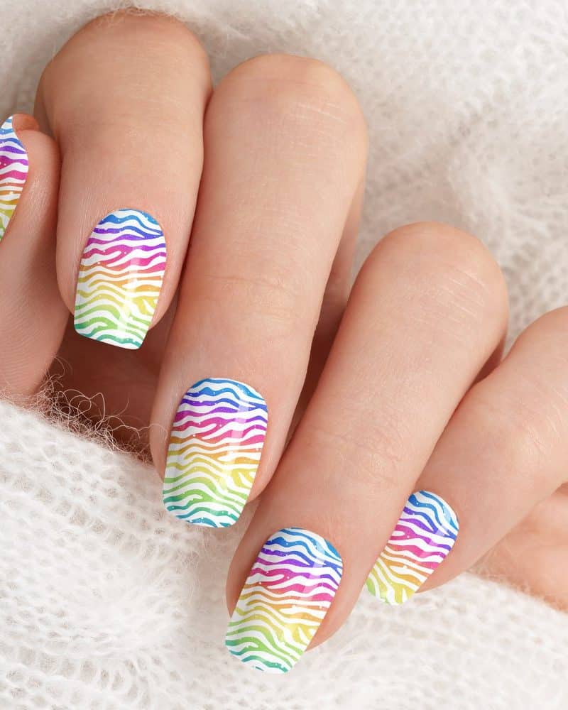 Closeup of a hand with fingernails painted with a rainbow zebra stripe design.