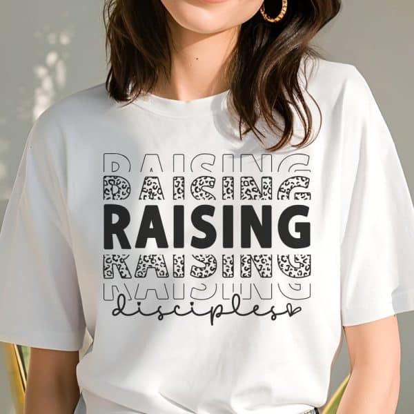 White T-Shirt With The Word Raising Repeated In Different Fonts, Some With A Leopard Print Design, And The Word Disciples Below.