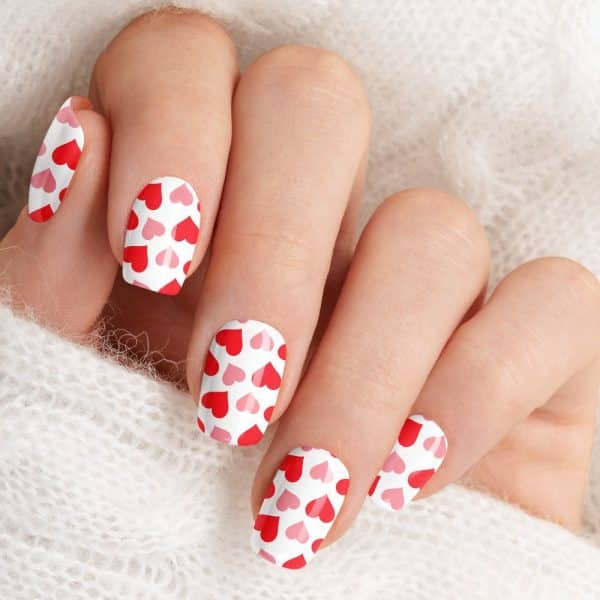 Close-Up Of A Hand With Fingernails Decorated With A Red And Pink Heart Pattern.