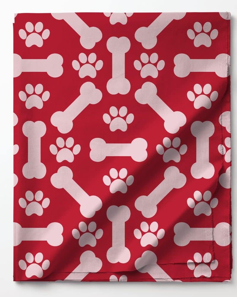 Red fabric with a repeating pattern of pink bones and paw prints.