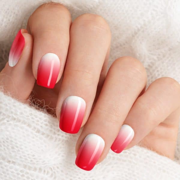 Close-Up Of A Hand With Ombre Nails, Transitioning From White To Bright Red.
