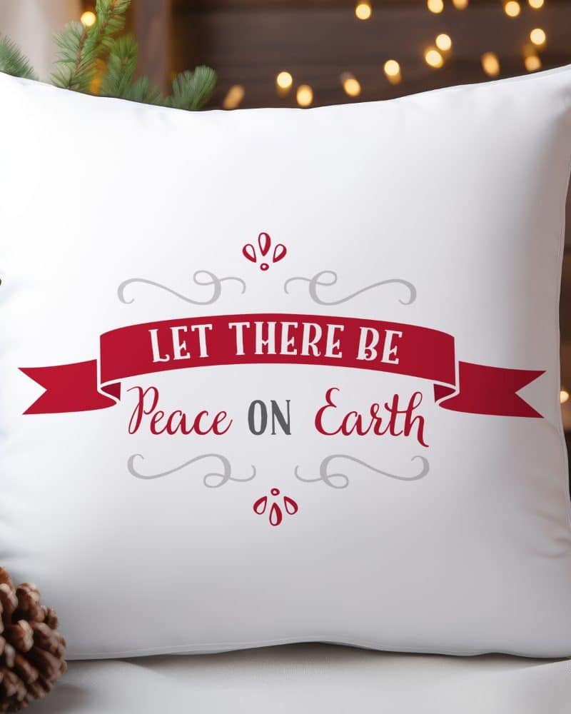 White pillow with red and gray text reading Let There Be Peace on Earth.